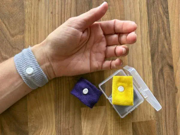 Hochwertige Stoffbündel in Gelb und Lila, ideal für DIY-Projekte und Näharbeiten, präsentiert auf Holzoberfläche mit Hand im Hintergrund.