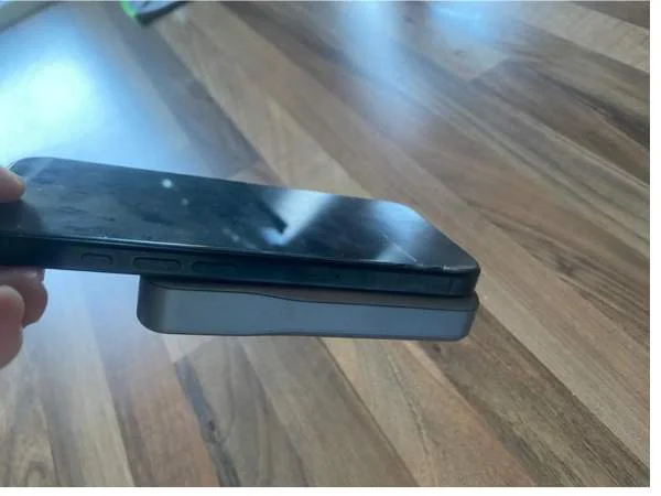 Smartphone mit kabellosem Ladegerät auf Holztisch, Nahaufnahme, moderne Technologie, mobiles Laden, drahtloses Aufladen, elektronische Geräte, Technik im Haushalt, innovative Ladetechnologie, Alltagsg.