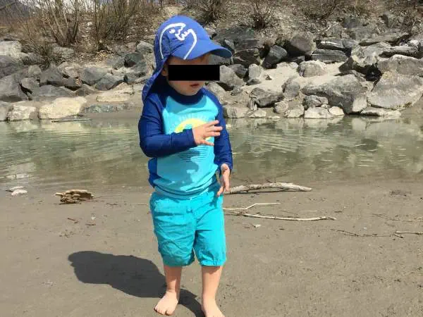 Kinder im Sommer am Flussufer, spielend und planschend, mit Sonnenhut und Badebekleidung, Naturumgebung, Familienaktivität, Outdoor, kindgerechtes Erlebnis, Sommerurlaub, Wasser, Spaß, Naturerkundun.