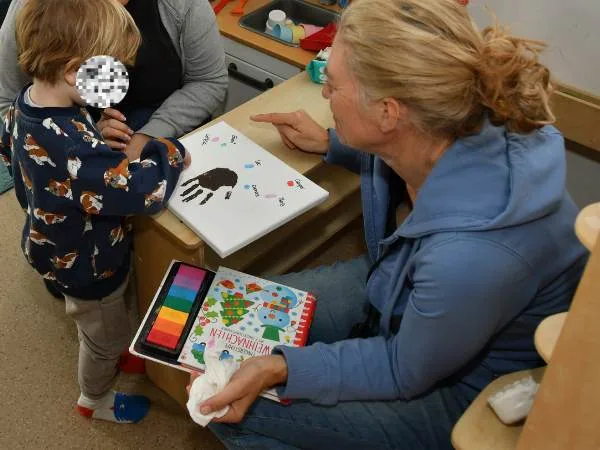 Ein Kind und eine erwachsene Frau beim kreativen Malen und Basteln, gemeinsames Bastelprojekt mit Farben und Papier, förderliche Aktivitäten für Kinder, Eltern-Kind-Zeit, kreative Beschäftigung.