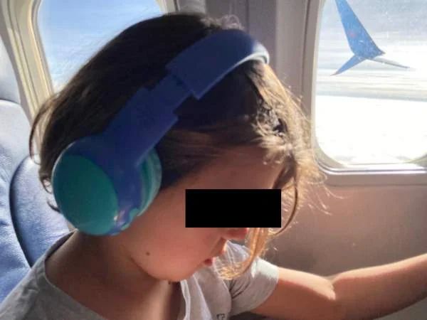 Kinder mit Kopfhörern im Flugzeug, Kind sitzt am Fenster, Flugreise, Kinderreise, Familienurlaub, Flugzeug, Kindermode, Reise mit Kindern, Flugzeugabenteuer, Elternblog, Familienreise, Flugzeugkomfor.