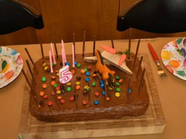 Leckere Schokoladentorte mit bunten Streuseln, Kerzen und Dinosaurier-Topper für Kindergeburtstag, perfekt für festliche Anlässe und Familienfeiern.