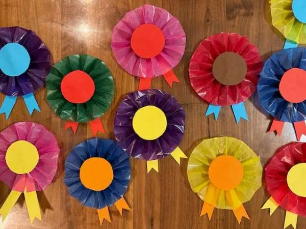 Bunte Papierrosetten mit bunten Schleifen, ideal für kreative Bastelideen zum Kindergeburtstag und zum Steckenpferd Basteln.