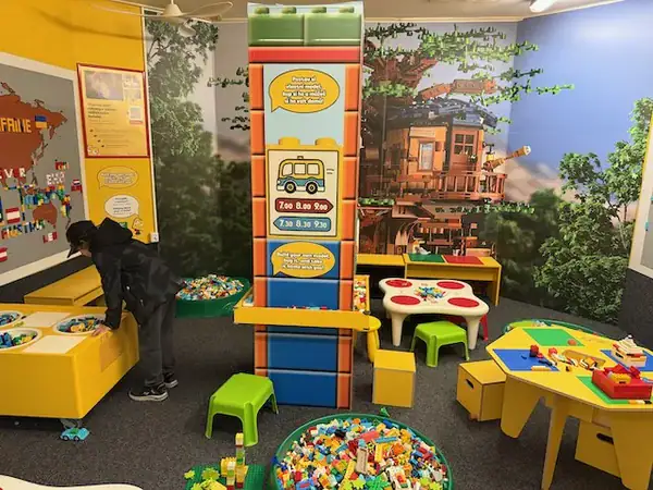 Spielbereich für Kinder mit bunten Bausteinen und Spieltischen in einer Indoor-Spielhalle.