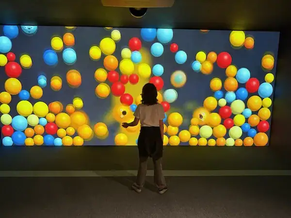 Kinder spielen in einer bunten Ballhalle mit gelben, blauen, roten und orangefarbenen Bällen, ideal für Indoor-Aktivitäten bei schlechtem Wetter.