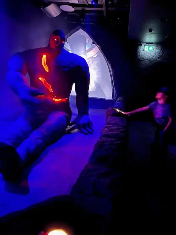 Kunstinstallation mit leuchtenden Elementen und dunkler Atmosphäre in einer Indoor-Umgebung.