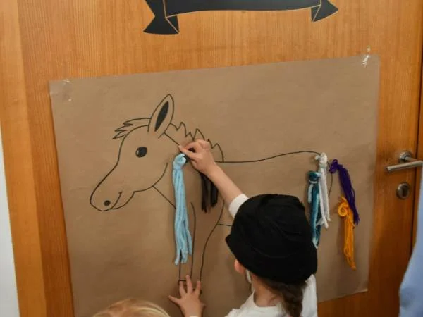 Regenbogen-Haustier-Kunstprojekt mit bunten Stoffen und Kind beim Malen eines Einhorns, kreative Bastelaktivität für Kinder, pädagogisches Spiel, kindgerechte Kunst im Kindergarten, bunte Dekorationen.