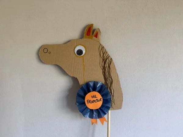Ein handgefertigtes Holzpferd mit bunten Details und einer blauen Auszeichnung, ideal für Kinderzimmerdekoration und kreative Spielideen für kleine Pferdeliebhaber.
