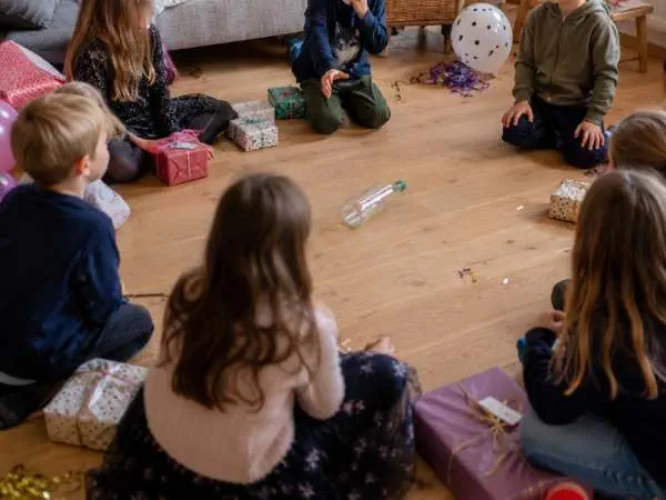 Fröhliche Kinder spielen im Kreis mit Geschenken und Ballons bei einer Kinderparty, die Spaß und Gemeinschaft fördert. Perfekt für Familien- und Kinderveranstaltungen.