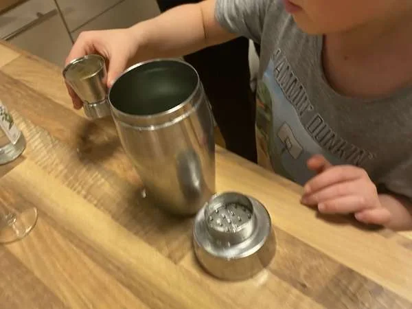 Kind öffnet einen Cocktailshaker beim Kindercocktails mixen