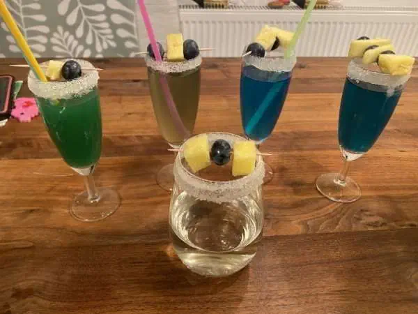 Bunte alkoholfreie Kindercocktails mit Zuckerrand und Fruchtspießen