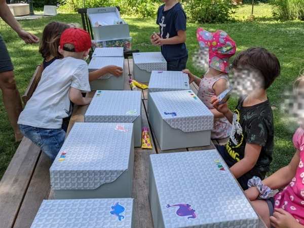 Kinder gestalten am Tisch ihre Dino-Landschaft im Karton beim Kindergeburtstag