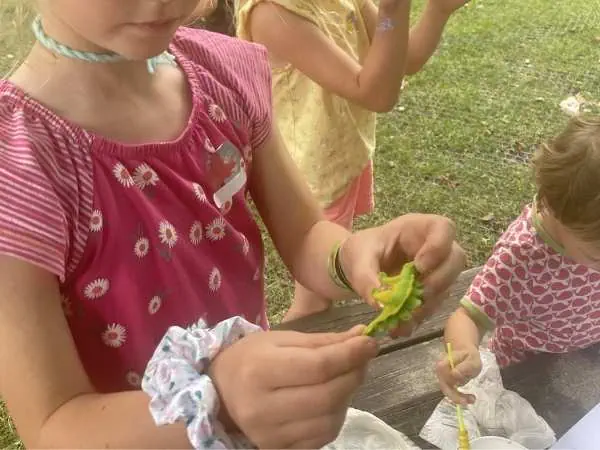 Kind gestaltet beim Kindergeburtstag eine Figur aus Playmais für die Dino-Landschaft