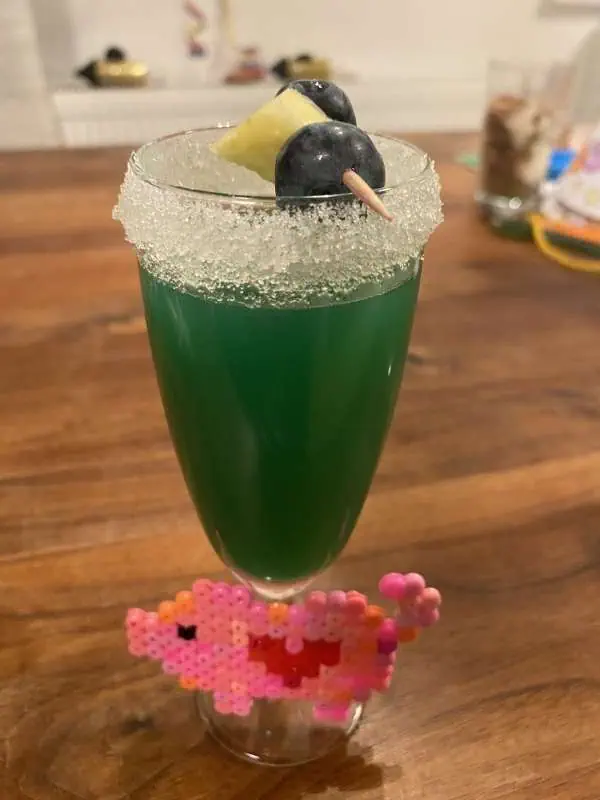 Grüner alkoholfreier Kindercocktail mit Zuckerrand und Beerenspieß