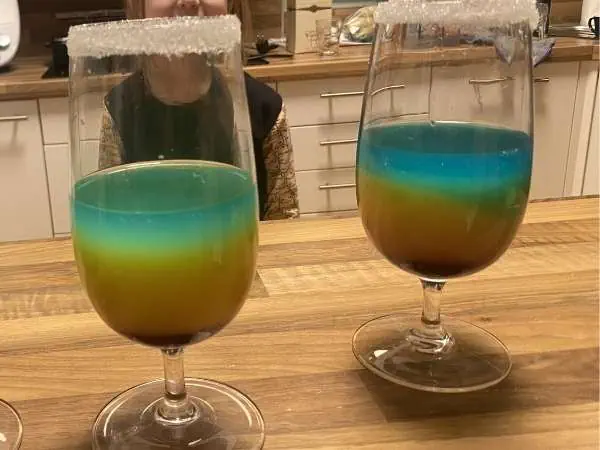 Zwei geschichtete Kindercocktails in Blau, Grün und Orange mit Zuckerrand