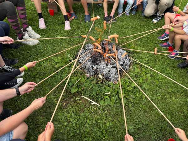 Kinder grillen Würstel am Lagerfeuer im Kinderhotel Felben