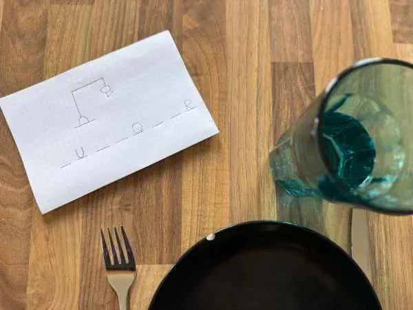 Galgenmännchen auf kariertem Papier auf einem gedeckten Restauranttisch