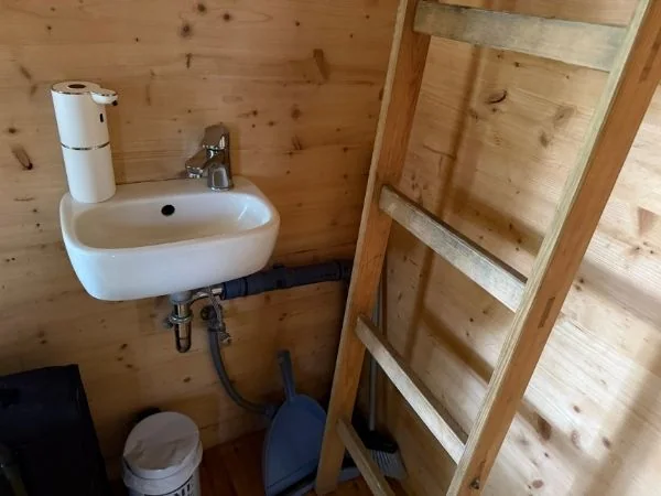 Kleines Waschbecken und Leiter zum Schlafplatz im Giebel des Baumhauses