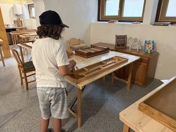 Kind von hinten mit Kappe spielt an einem großen Holzspiel im Holtarium