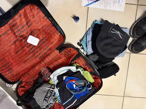 Gepackter Koffer für Südafrika mit Übersetzungskopfhörern, GoPro und Kleidung