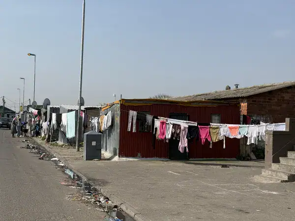 Wellblechhaus im Vordergrund und formelle Wohnhäuser im Hintergrund in Langa