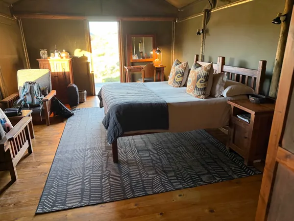 Großes Schlafzimmer im Familienzelt der Buffelsdrift Game Lodge mit Doppelbett, Holzmöbeln und Ausgang zur Terrasse