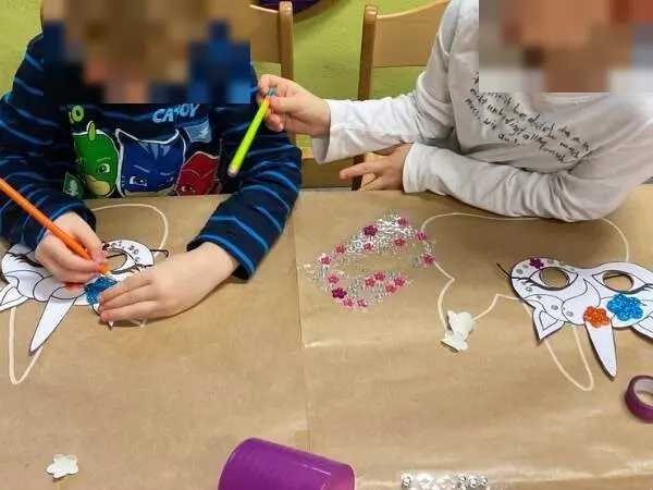 Zwei Kinder verzieren Einhorn-Masken mit Stiften und Glitzersteinen beim Einhorn-Geburtstag